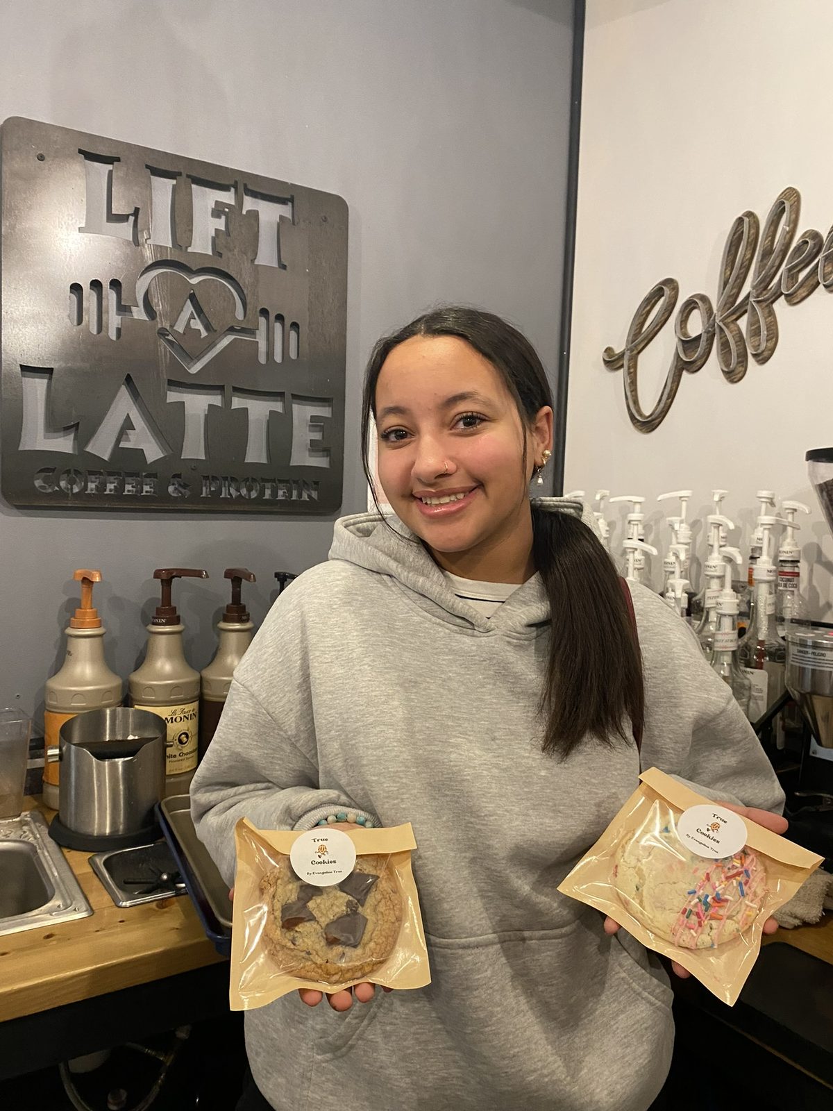Evangeline holding bagged True Cookies treats at Lift A Latte coffee shop