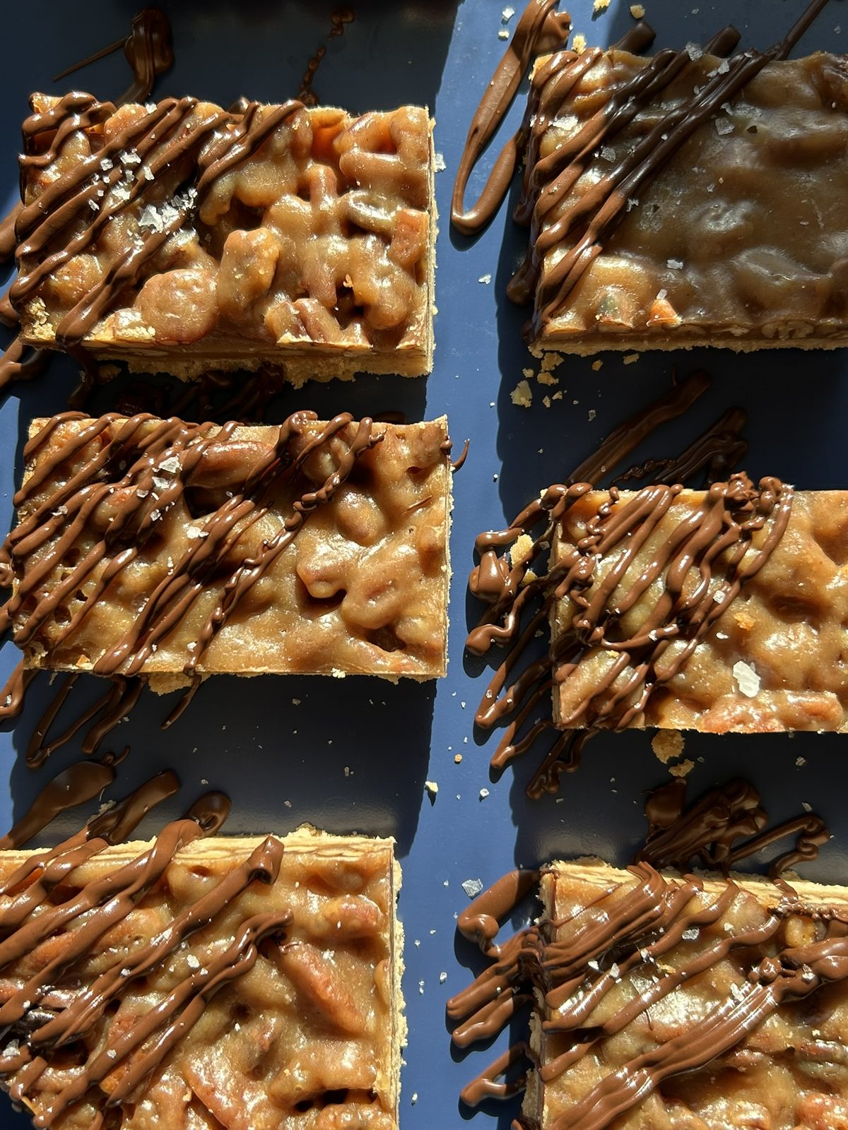 Caramel pecan bars drizzled with chocolate and flaky salt