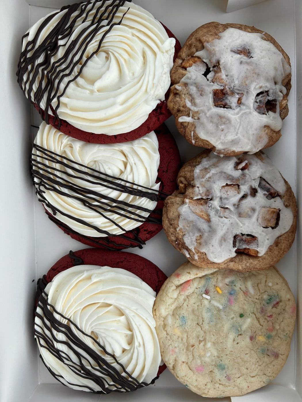Box of red velvet cookies with cream cheese frosting