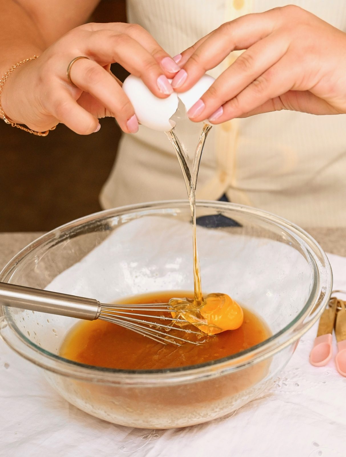Cracking an egg into a mixing bowl of caramel batter